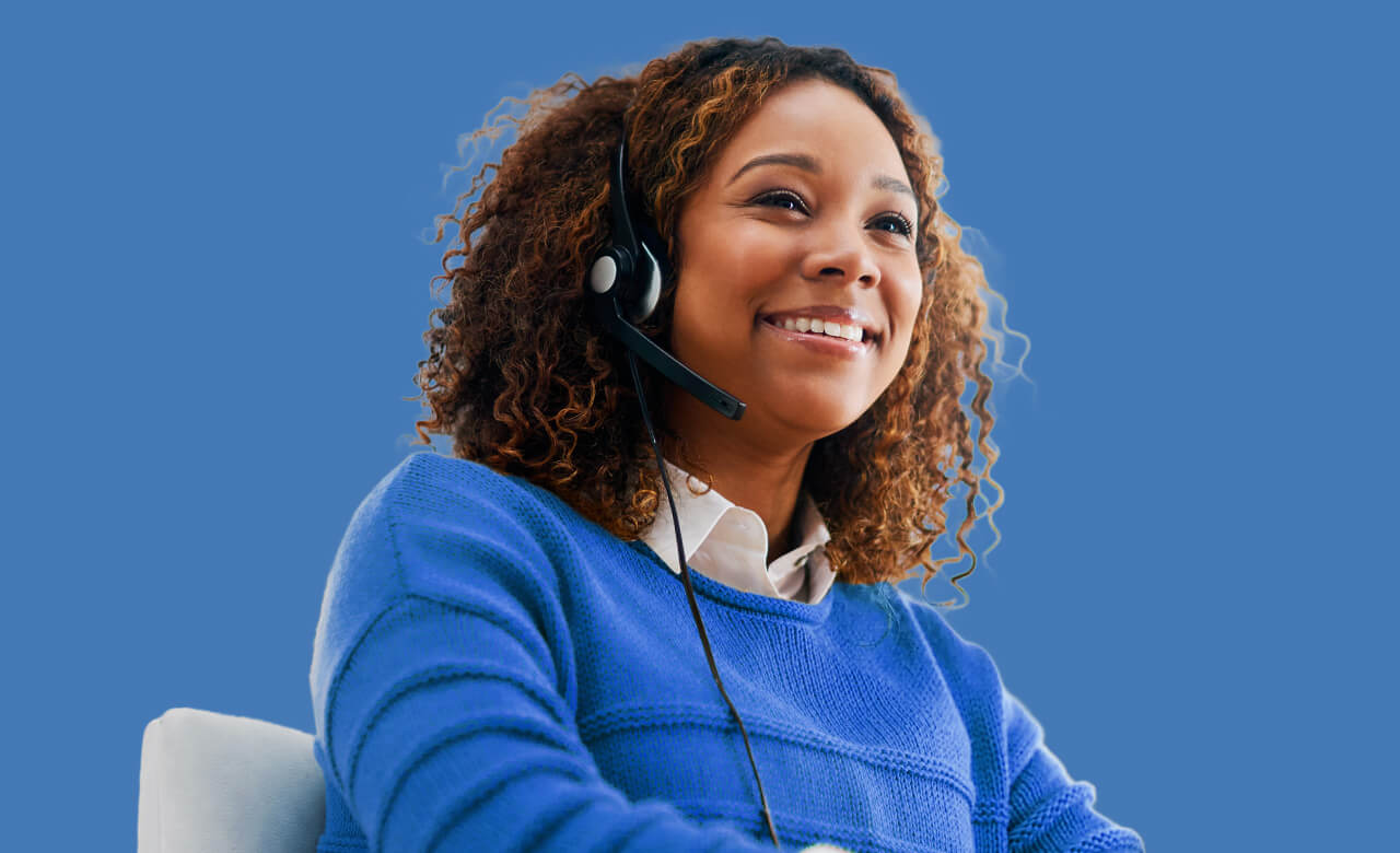 Woman smiling with headset wearing a blue jumper, on blue blackground