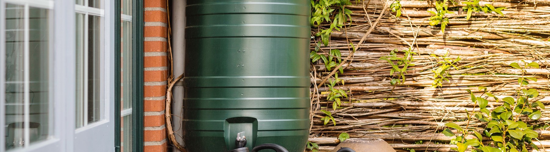 Water butt in garden with watering can