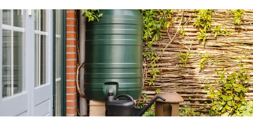 Water butt in garden with watering can