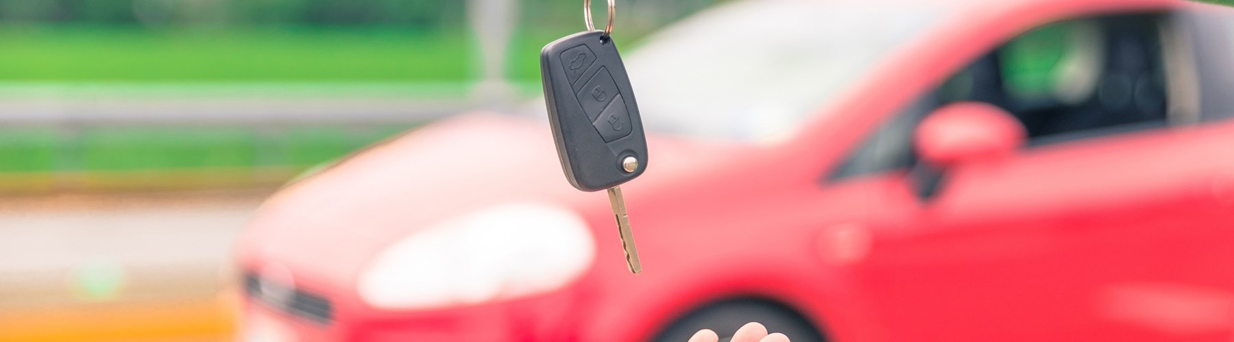 Car keys being delivered in front of red car
