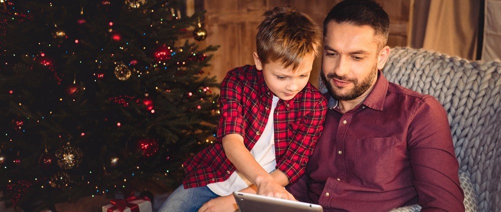 Father and son with tablet by Christmas tree