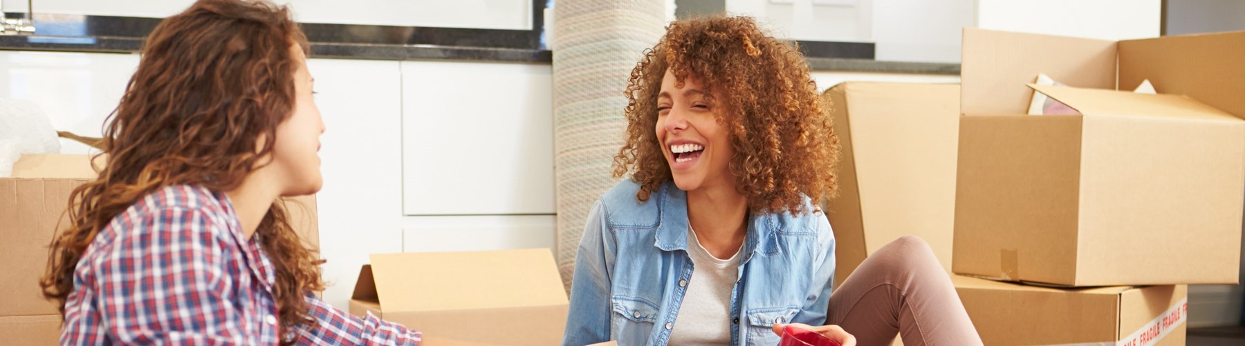 Female friends unpacking and laughing in new home