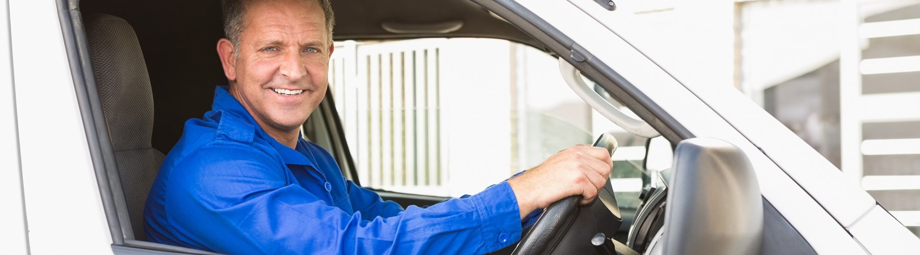 Smiling man driving a white van