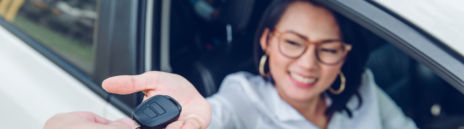 Young woman in car receiving car key