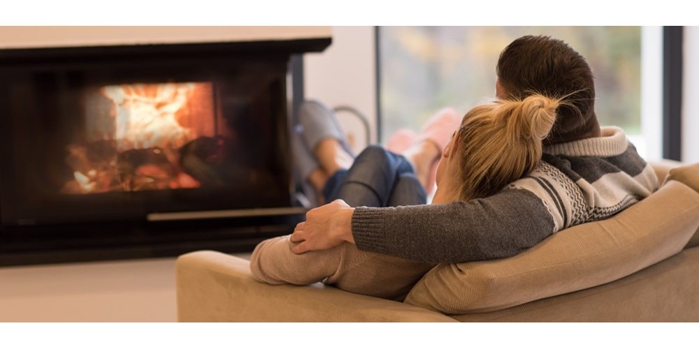 Couple sitting on sofa in front of fire