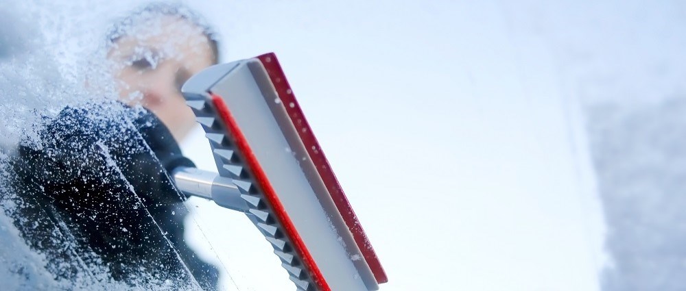 Woman scraping windscreen on snowy day