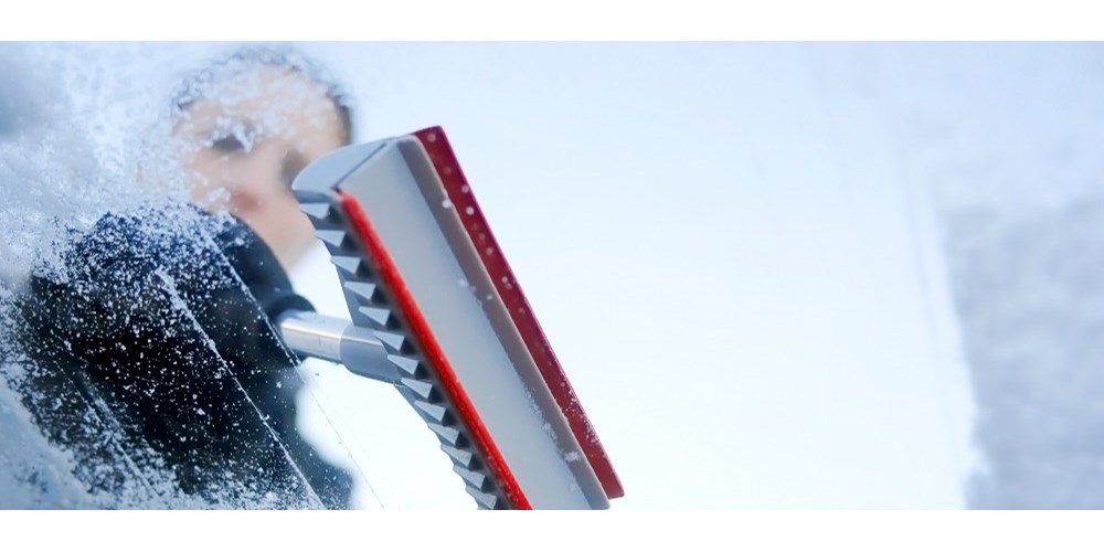 Woman scraping windscreen on snowy day